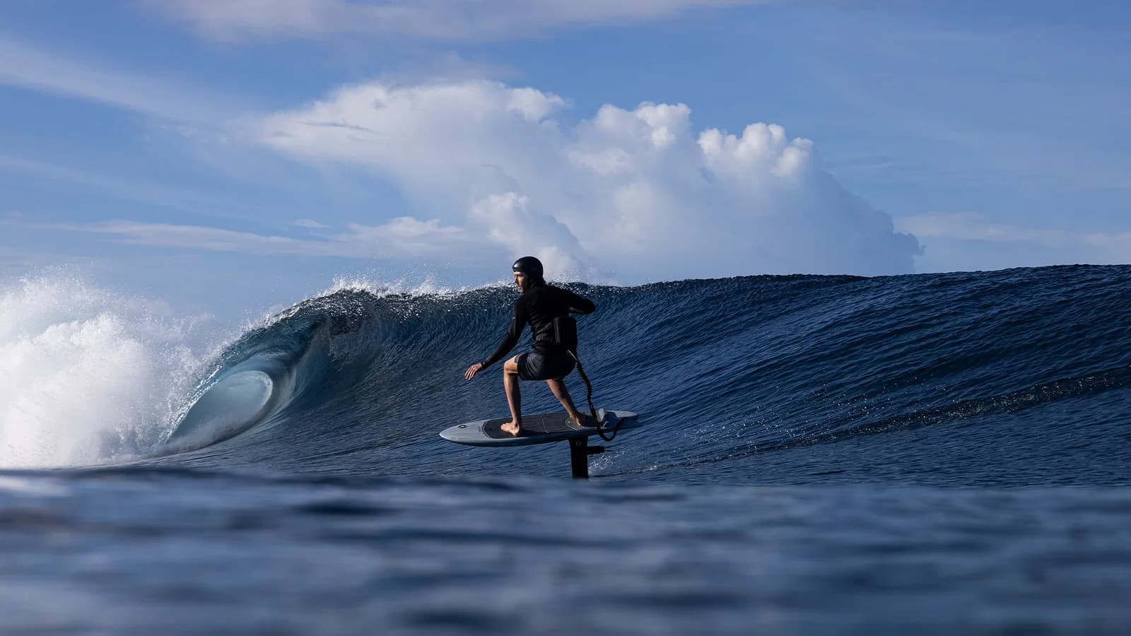 Blue-shirt rider holding the throttle on a clean wave